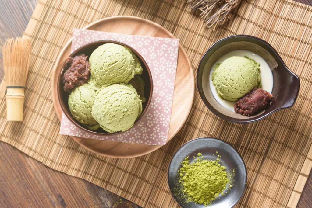 Top view of Homemade green tea or matcha ice cream in the wooden bowl with sweet red bean and put on bamboo mat